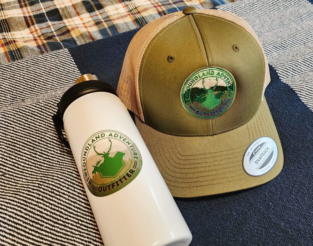 Newfoundland Adventures branded hat and water bottle rest at the foot of the bed in the hunting lodge to welcome guests