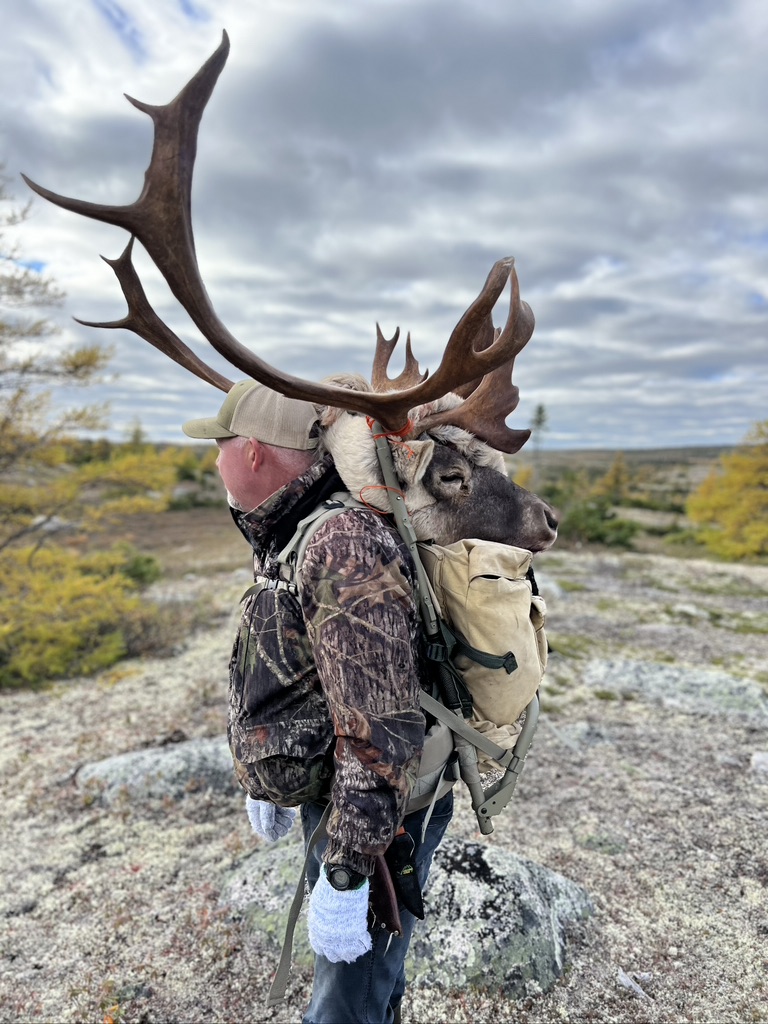 Hunter carrying caribou head on his back after successful wilderness hunt in Newfoundland