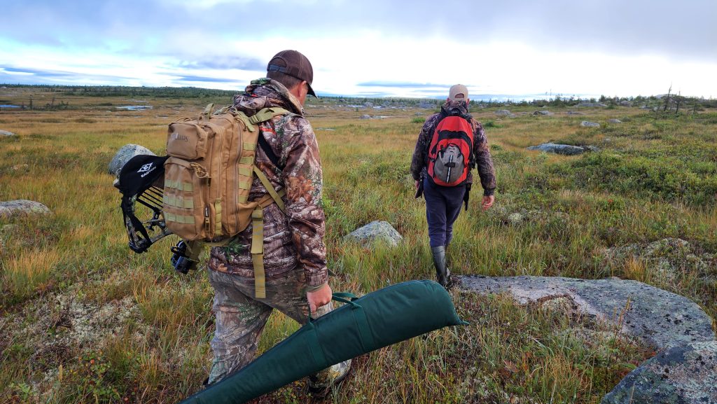 Two men carry their hunting gear as they trek along the rocky Newfoundland landscape in search of big game